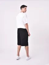 Bermuda de jean color verde claro lavado, corte recto y largo hasta la rodilla. Presenta costuras visibles y bolsillos tipo cargo en los laterales.