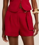 Short de vestir rojo de cintura alta, con cinto de hebillas media luna dobles en la cintura, pliegues y bajo plegado.