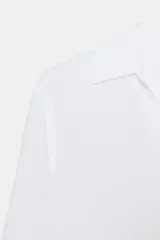 Camisa de manga larga color marrón oscuro, con cuello solapa, escote pico pronunciado y bajo asimétrico redondeado.