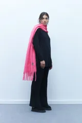 Bufanda rectangular de poliéster, color rosa chicle, con flecos en los extremos.