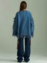 Sweater azul con bordado central en forma de trenza, detalles laterales a cuadros y terminaciones desflecadas. Tiene corte oversize, cuello redondo y tajos laterales con cordones.