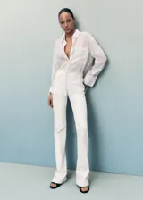 Jeans Fiona de tiro medio y corte flare con bajo deshilachado, confeccionados en tejido denim de algodón con elasticidad. Presentan diseño clásico de cinco bolsillos, trabillas para cinturón y cierre delantero con cremallera y botón metálico.