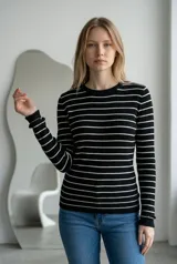 Sweater de hilo de punto con diseño de rayas horizontales negras sobre fondo blanco, cuello redondo y mangas largas.