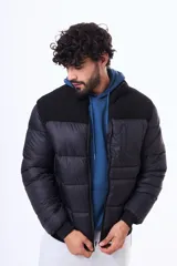Campera puffer negra con paneles de textura tipo corderito en la parte superior del pecho y hombros. Cuenta con cierre frontal, puños y ruedo acanalados, y un bolsillo vertical con cierre en el pecho.