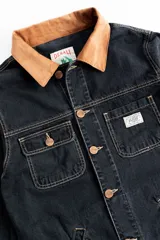 Campera corta de jean negro con cuello de pana marrón, confeccionada en jean grueso 100% algodón de 14 onzas, con costuras marrones en contraste.
