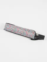 Paraguas plegable automático con funda protectora estampada con diseño floral en tonos rojos, blancos y amarillos. Cuenta con mango ergonómico negro y correa de sujeción.