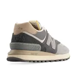 Championes urbanos New Balance modelo 574, con diseño en tonos grises y detalles en marrón. Confeccionados en una combinación de gamuza y malla, cuentan con el logo lateral característico y entresuela con tecnología ENCAP para mayor amortiguación.