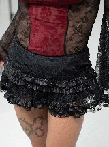 Pollera mini tipo skort de color negro, con diseño de volados en capas y detalles de encaje. Incluye short integrado para mayor comodidad.