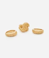 Kit de tres anillos de metal reciclado con diseño robusto y texturizado. El conjunto incluye dos anillos de banda ancha con textura y un anillo central con diseño de nudo.