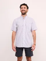 Camisa de manga corta con cuello abotonado y estampado de cuadros finos en tonos azul y rosado sobre fondo blanco.