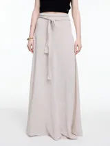 Falda larga color beige, de corte evasé y tiro alto, con lazo ajustable en la cintura.
