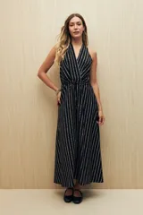 Vestido largo negro con estampado de líneas verticales blancas, escote halter y cintura con lazo.