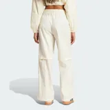 Pantalón deportivo Adidas de corte holgado en color blanco, con cintura elástica y diseño de tres tiras negras verticales en los laterales que incorporan detalles de red y el logo de la marca.