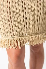 Vestido corto dorado tejido al crochet, con breteles finos y flecos en el ruedo.