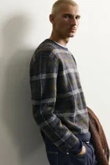 Jersey de punto con lana, de corte relajado, cuello redondo y manga larga. Presenta un diseño de cuadros en tonos oscuros con acabados en rib en cuello, puños y bajo.
