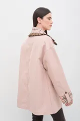 Chaqueta rosada de corte holgado con detalles en estampado de cuadros escoceses en el cuello, puños y solapas de los bolsillos. El cuello presenta un acabado con volados y el cierre es frontal con botones.