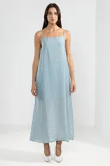 Vestido largo hasta el tobillo color celeste, de tejido arrugado liviano, con escote recto y breteles finos. Presenta lazos en los costados, forro hasta arriba de las rodillas y caída posterior más larga.