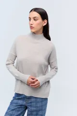 Polera tejida de punto confeccionada en lambswool color gris claro, con cuello alto y calce holgado.