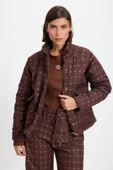 Campera de abrigo con cuello alto y manga ranglan, confeccionada en tela capitoneada con relleno y forro interno. Presenta un diseño estampado con motivos geométricos y paisley en tonos azules y marrones.