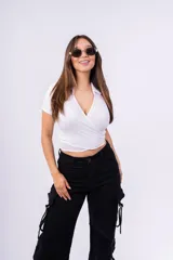 Top negro de punto canalé con cuello tipo chomba, corte cropped y diseño cruzado con abertura en la cintura.