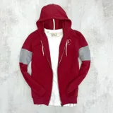 Campera con capucha roja con mangas grises, cierre frontal y bolsillos laterales.