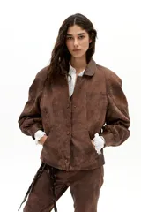 Chaqueta oversized de cuero de oveja color marrón antiguo, con hombros exagerados, cuello camisero redondeado, bolsillos frontales y botones a presión forrados. Cuenta con forro capitoneado y bolsillo interno.
