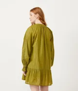 Vestido corto de manga larga en color verde oliva, confeccionado en tejido plano con hilos metalizados a contraste. Presenta cuello redondo con lazo decorativo y flecos, mangas largas con puños elásticos y detalle de volados en los puños.