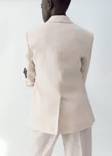 Blazer de lino color beige, de diseño recto con cuello en V, solapas con muesca, mangas largas, bolsillos de ribete delanteros y cierre frontal de un botón.