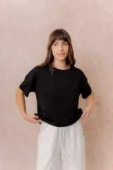Remera negra de corte oversize con cuello redondo, mangas cortas amplias, hombros caídos y recortes delanteros.