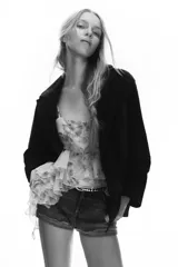 Shorts de jean de algodón, tiro alto, color azul claro desgastado. Presenta cinco bolsillos, cierre frontal con botón metálico y cremallera, y bajo desflecado con vuelta.