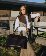 Bolso tipo tote de cuero negro con textura tipo piel de cocodrilo, doble asa de mano y cierre superior con cremallera.