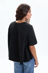 Remera negra de manga corta con corte evasé, que se ensancha ligeramente hacia el bajo.