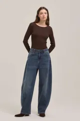 Jean de corte wide leg y tiro alto, con diseño de pierna curva o tipo barril, en tono azul medio con efecto lavado.