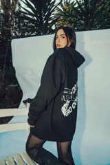 Hoodie negro oversize con capucha y estampado con texto en la espalda.