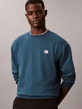 Buzo Calvin Klein de cuello redondo, color azul, confeccionado en algodón terry, con puños y dobladillo de punto canalé y parche con mini monograma de la marca en el pecho.