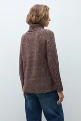 Polerón de cuello alto confeccionado en tejido buclé con textura jaspeada, de corte holgado y mangas largas con diseño raglán.