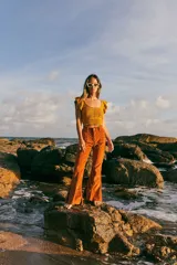 Top tejido color mostaza con lurex, escote redondo y volados en los hombros.