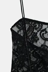 Top de encaje negro con cuello alto, mangas largas acampanadas, corsé interior estructurado y bajo asimétrico.