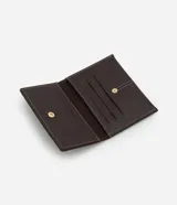 Billetera sobre de tamaño pequeño confeccionada en poliuretano color marrón oscuro, con detalle de pespuntes en hilo blanco y cierre mediante botón a presión.