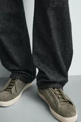 Zapatilla urbana de hombre confeccionada en piel con acabado de serraje, diseño minimalista con cordonera oculta y suela de goma a contraste.