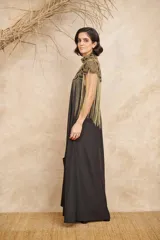 Capa negra con cuello alto y bordados dorados. Presenta flecos largos dorados que caen desde los hombros.