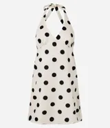 Vestido corto blanco con estampado de lunares negros, escote en V y espalda descubierta con tiras ajustables en el cuello.