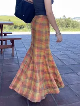 Falda larga de lino con estampado escocés en tonos otoñales (naranja, amarillo, marrón y rojizo). Diseño con gajos que le otorgan mucho movimiento, ajustada en la cadera y con vuelo en el ruedo (corte sirena o trompeta).