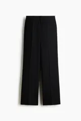 Pantalón sastrero de tiro alto y color negro, con piernas rectas, raya marcada al frente y bolsillos laterales al bies.
