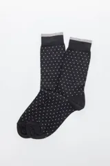 Par de medias negras con pequeños lunares blancos y puño gris.