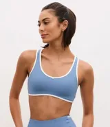 Top deportivo de microfibra con diseño de espalda nadador, escote redondo y bies en color blanco a modo de contraste. Cuenta con copas desmontables para mayor soporte y ajuste.