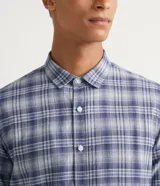 Camisa de franela de manga larga con estampado de cuadros en tonos azul y gris. Tiene cuello camisero y cierre frontal con botones.