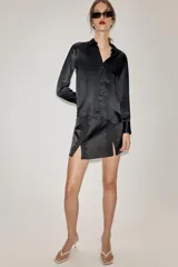 Falda pantalón negra de satén con detalles de encaje vertical y aberturas frontales. Cuenta con cierre lateral oculto.