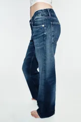 Jeans wide leg de tiro bajo y cinco bolsillos con efecto lavado y cierre frontal con cremallera y botón metálico.