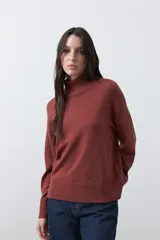 Polera de tejido liviano en color negro, con cuello alto, mangas largas y corte relajado. Presenta un diseño minimalista con recortes laterales que aportan estructura a la prenda.